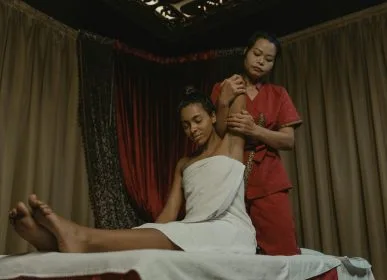 A soothing spa session with a woman receiving a massage indoors, wrapped in a towel.